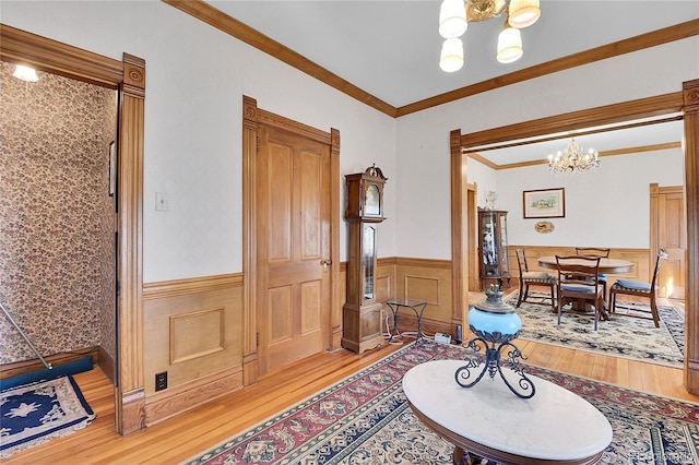 entrance foyer with light wood-type flooring, a chandelier, crown molding, and wainscoting