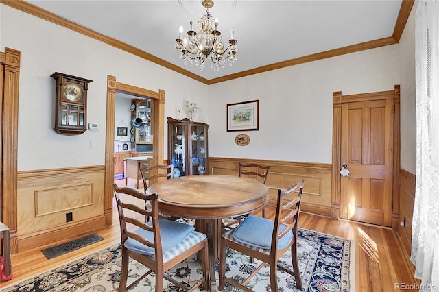 dining space featuring light wood-style floors, a wainscoted wall, and visible vents