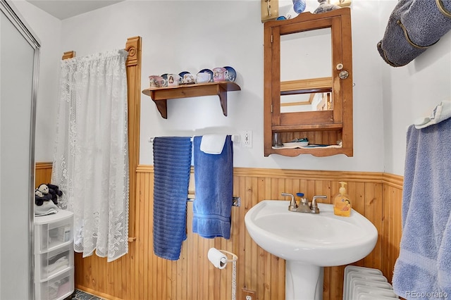 bathroom featuring a wainscoted wall, wooden walls, and radiator heating unit