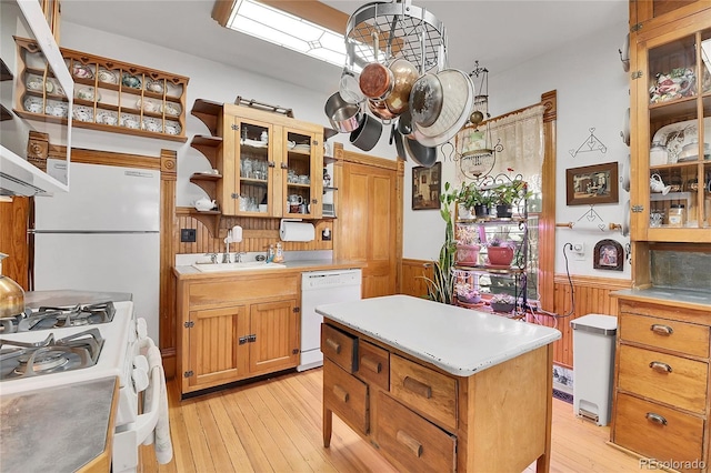 kitchen featuring white appliances, light wood finished floors, light countertops, and wainscoting