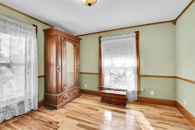 empty room featuring baseboards, ornamental molding, light wood-type flooring, and a healthy amount of sunlight