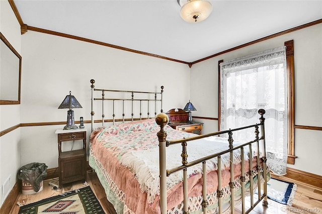 bedroom featuring baseboards, wood finished floors, and crown molding