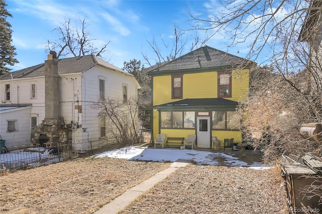 back of property with a shingled roof, a patio area, and fence