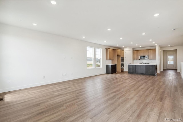 6384 E 154th Pl, Thornton, CO 80602 - unfurnished living room with recessed lighting, baseboards, light wood finished floors, and a sink
