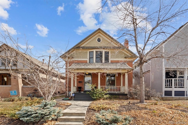 victorian house featuring brick siding, a chimney, and a porch