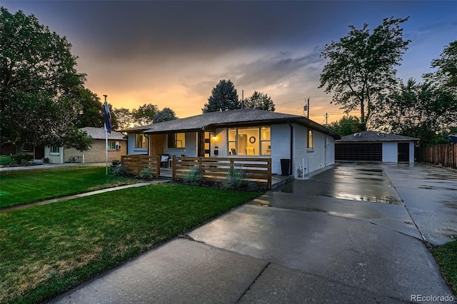 view of front of home featuring a garage, a yard, an outbuilding, and covered porch