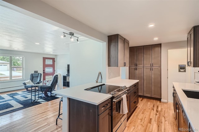 kitchen featuring electric stove, a kitchen bar, dark brown cabinetry, and light wood-type flooring