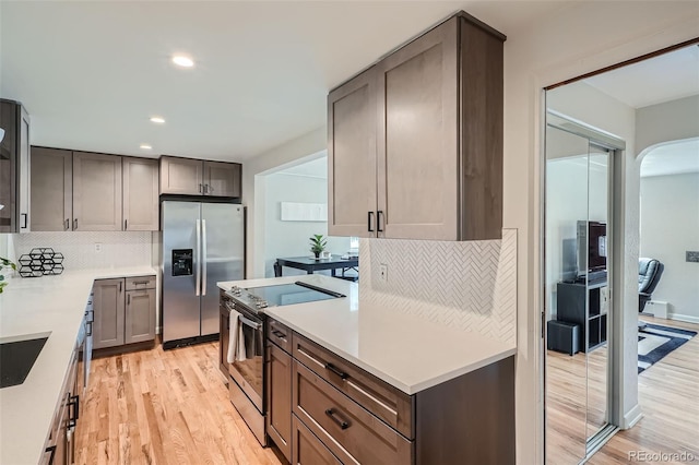 kitchen featuring appliances with stainless steel finishes, sink, light wood-type flooring, and decorative backsplash