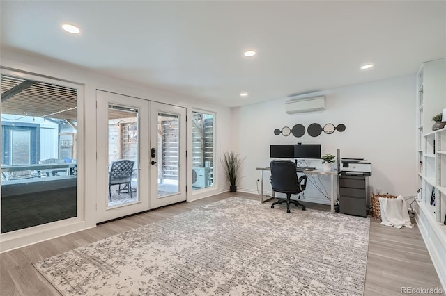 office area with a wall mounted air conditioner, light hardwood / wood-style floors, and french doors