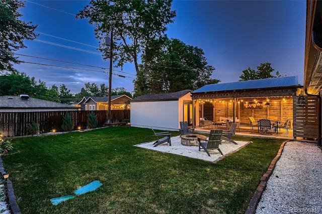 yard at dusk featuring a patio, an outdoor structure, and a fire pit