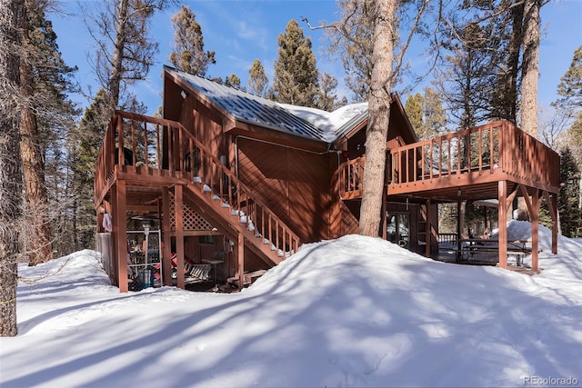 view of snow covered exterior featuring stairs, metal roof, and a deck