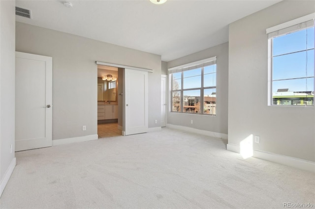 unfurnished bedroom with light colored carpet and ensuite bath