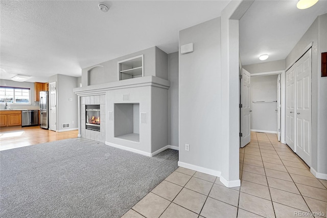 7511 S Sicily Way, Aurora, CO 80016 - unfurnished living room featuring light tile patterned floors, light colored carpet, baseboards, a fireplace, and built in shelves