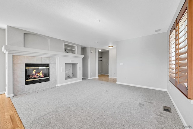 7511 S Sicily Way, Aurora, CO 80016 - unfurnished living room with arched walkways, baseboards, built in features, a tile fireplace, and carpet floors