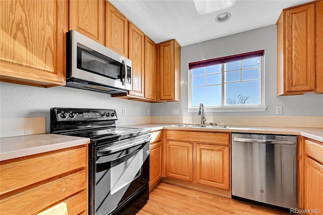 7511 S Sicily Way, Aurora, CO 80016 - kitchen featuring appliances with stainless steel finishes, a sink, light countertops, light wood finished floors, and brown cabinets
