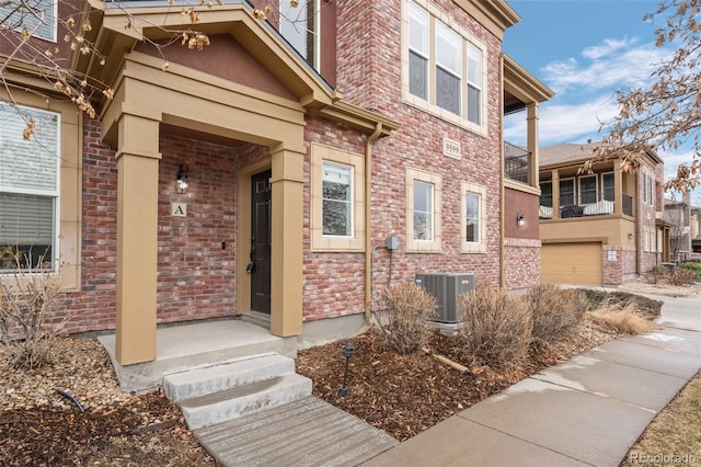 doorway to property featuring cooling unit and brick siding