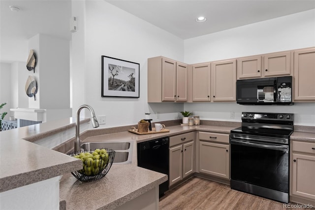 kitchen with light wood-type flooring, sink, and black appliances