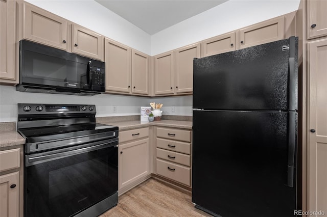 kitchen with light hardwood / wood-style floors, cream cabinetry, and black appliances