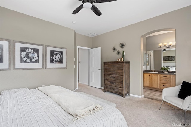 carpeted bedroom with ensuite bathroom and ceiling fan