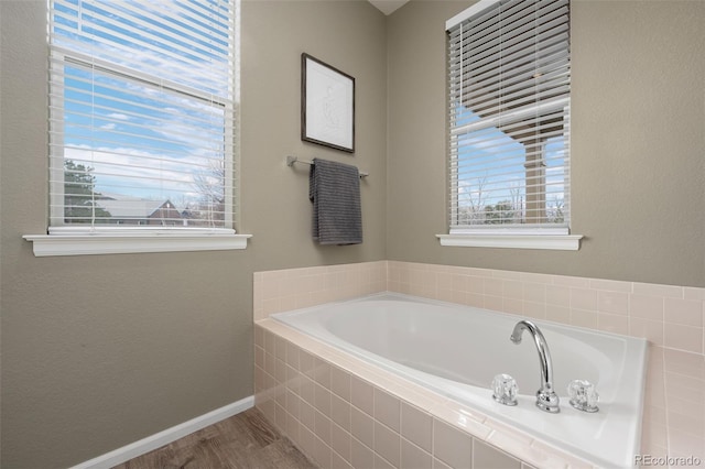 bathroom with tiled bath and hardwood / wood-style flooring