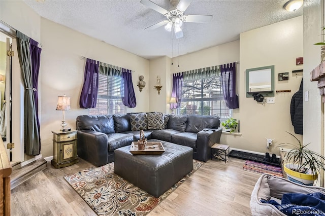 living room with ceiling fan, light hardwood / wood-style floors, and a textured ceiling