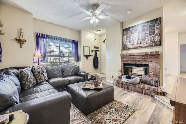 living room featuring a fireplace, ceiling fan, hardwood / wood-style floors, and a textured ceiling