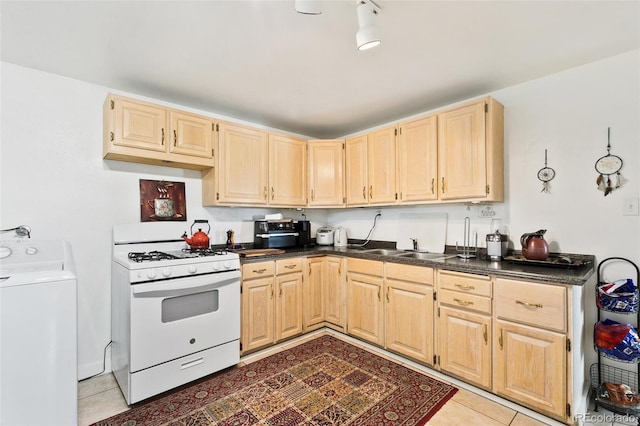 1512 E Monument St, Colorado Springs, CO 80909 - kitchen with washer / dryer, gas range gas stove, light brown cabinetry, dark countertops, and light tile patterned floors