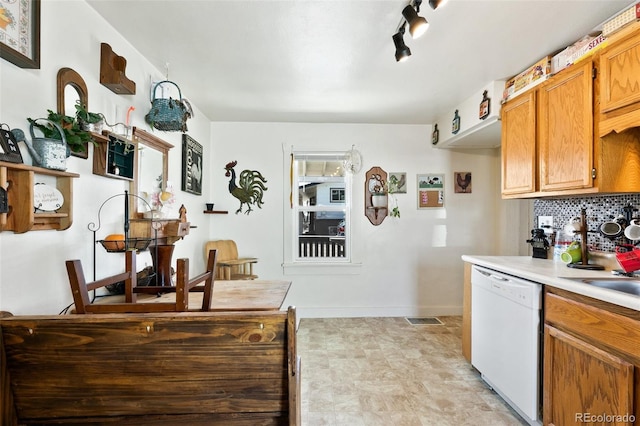 1512 E Monument St, Colorado Springs, CO 80909 - kitchen featuring white dishwasher, light countertops, backsplash, baseboards, and brown cabinets