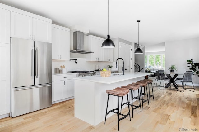 1541 Glencoe St, Denver, CO 80220 - kitchen featuring stainless steel appliances, wall chimney range hood, a sink, light wood-type flooring, and tasteful backsplash