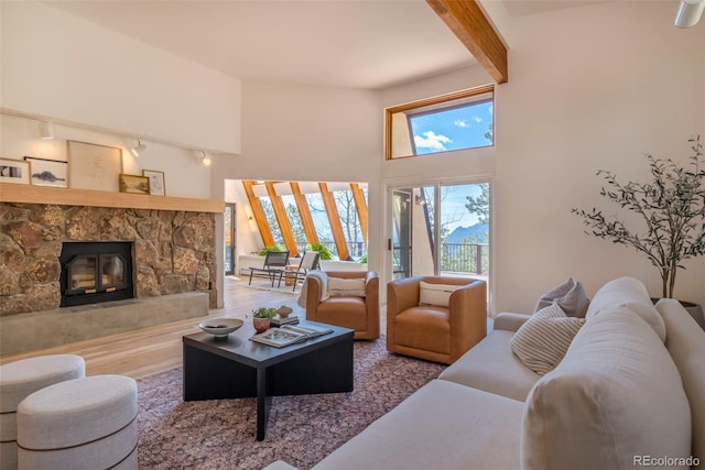 living room featuring beamed ceiling, a fireplace, hardwood / wood-style floors, and a high ceiling