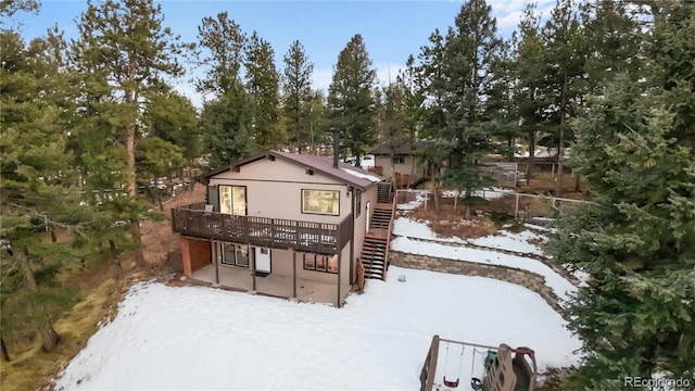 snow covered property with a deck, stairs, and a patio area