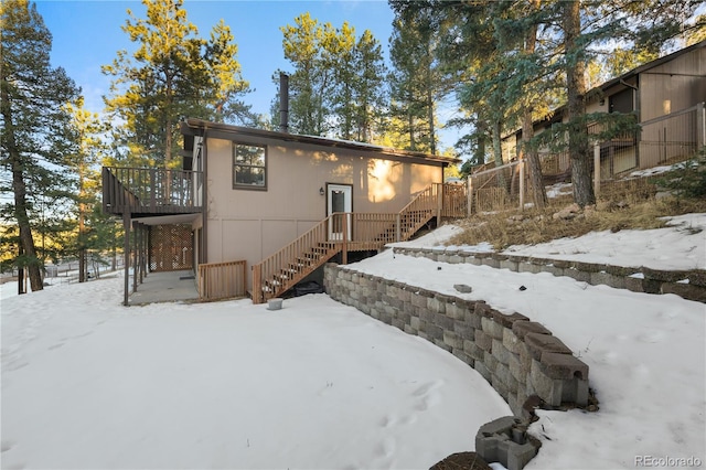 snow covered house with stairs and a deck