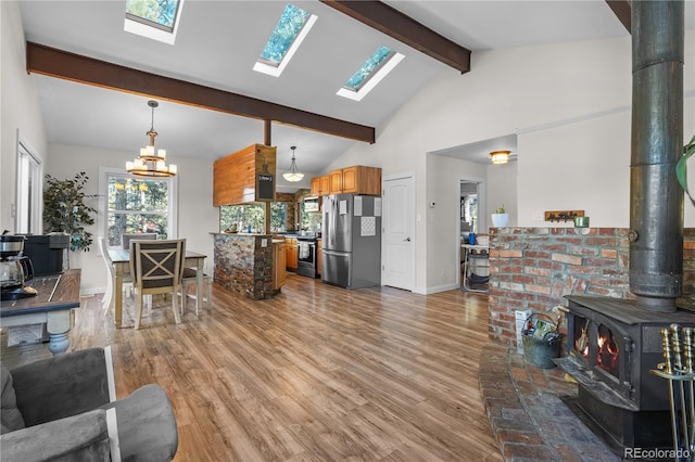 living area featuring baseboards, light wood finished floors, high vaulted ceiling, a wood stove, and beamed ceiling