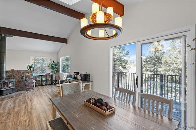 dining area featuring beamed ceiling, high vaulted ceiling, wood finished floors, and a wood stove