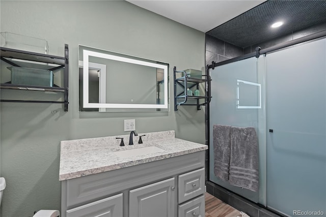 full bath featuring wood finished floors, vanity, and a walk in shower