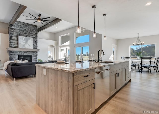 kitchen featuring beam ceiling, light stone countertops, sink, hanging light fixtures, and an island with sink