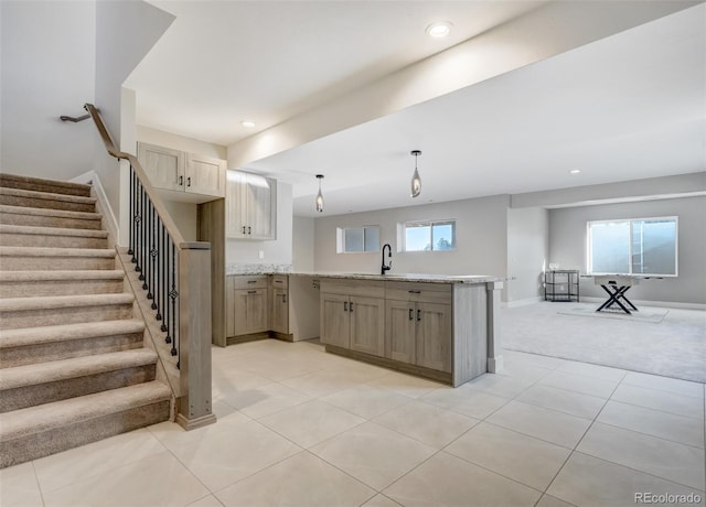 kitchen with light stone countertops, sink, pendant lighting, light carpet, and light brown cabinetry