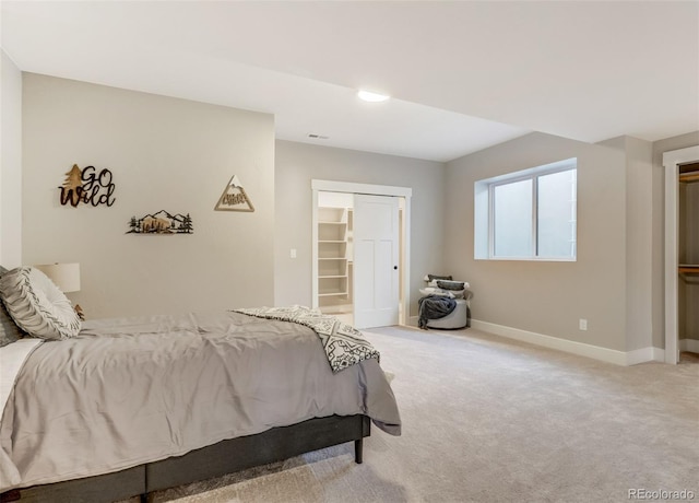 bedroom featuring a spacious closet, a closet, and light colored carpet