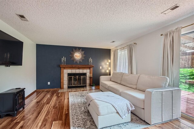 6057 S Pierson St, Littleton, CO 80127 - living area with a textured ceiling, wood finished floors, a wood stove, and a tiled fireplace