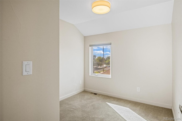 carpeted empty room featuring vaulted ceiling