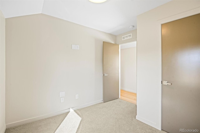 empty room featuring light colored carpet and vaulted ceiling