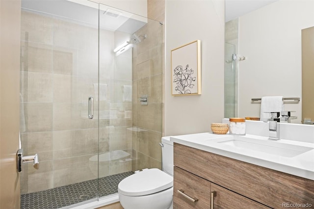 bathroom with a shower with door, vanity, and toilet