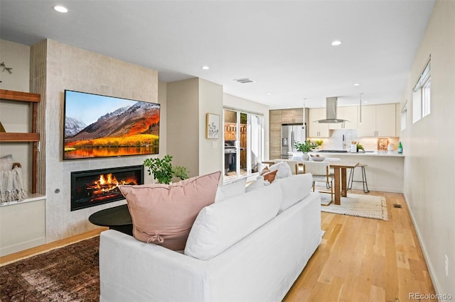 living room with a large fireplace and light wood-type flooring