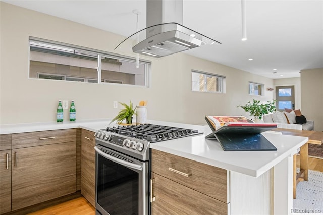 kitchen with island exhaust hood, gas range, kitchen peninsula, and light hardwood / wood-style flooring