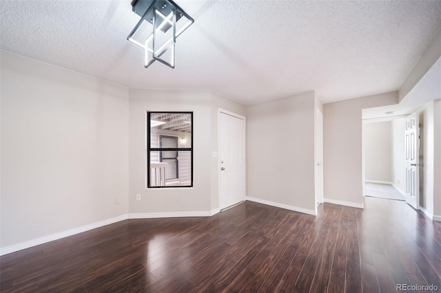 unfurnished living room with dark wood-type flooring and a textured ceiling