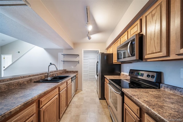 kitchen with appliances with stainless steel finishes, sink, and track lighting