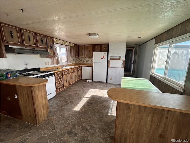 kitchen featuring sink, white appliances, kitchen peninsula, and decorative backsplash