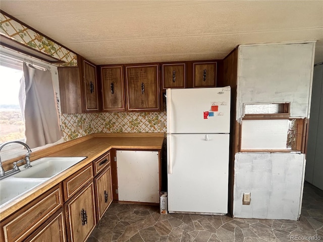 kitchen featuring white fridge, sink, and backsplash