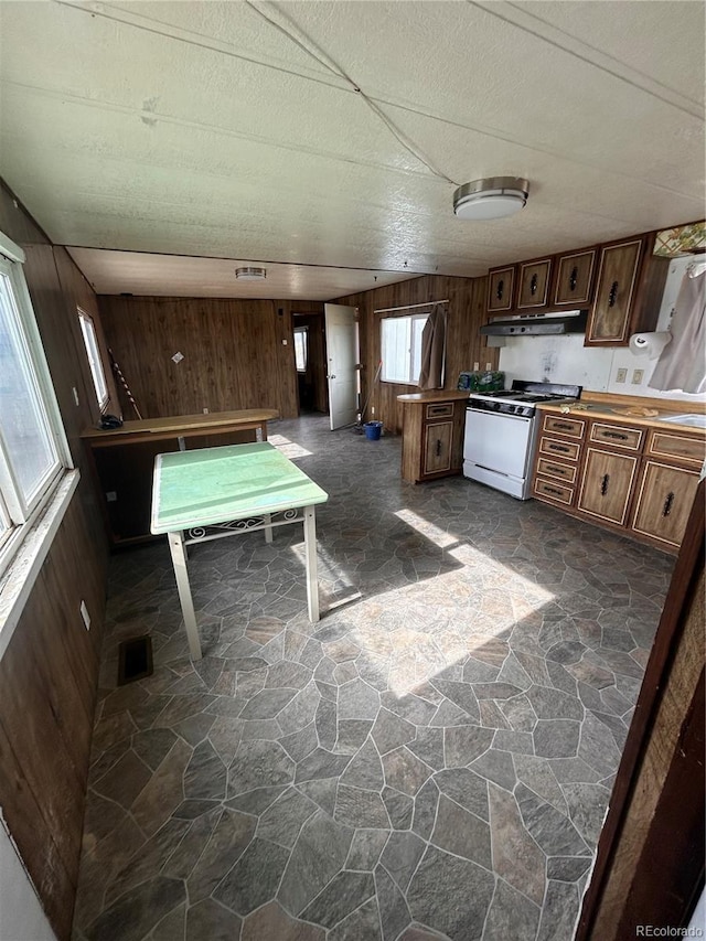 kitchen featuring wooden walls and white range with gas cooktop