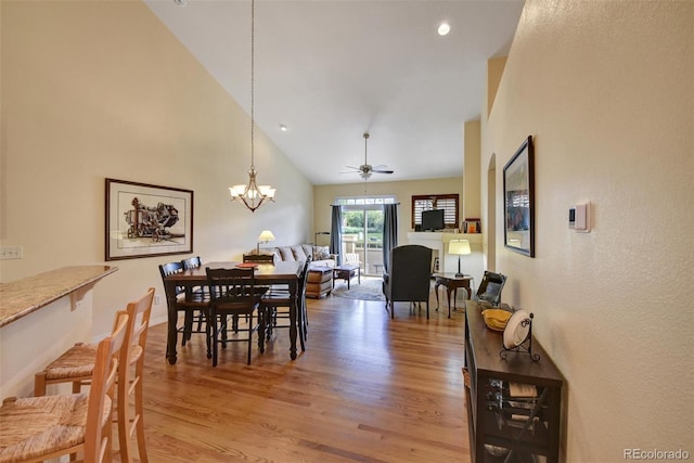 dining room featuring light wood finished floors, baseboards, ceiling fan with notable chandelier, high vaulted ceiling, and recessed lighting